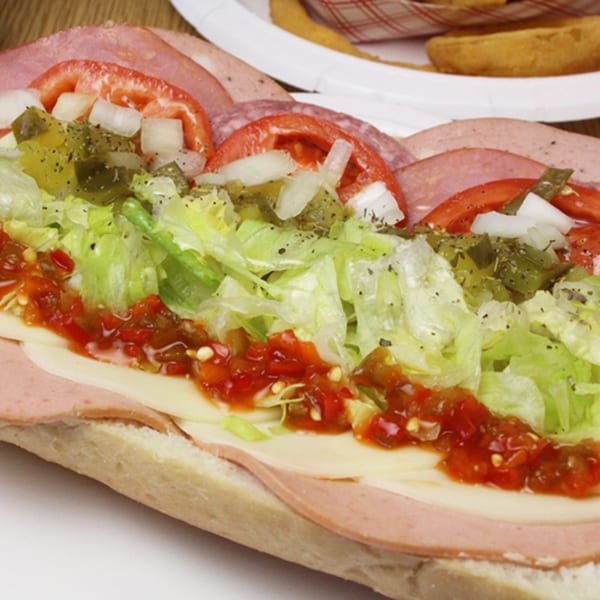 Close-up of a Backwoods Pizza sub sandwich with deli meats, cheese, lettuce, tomatoes, onions, and peppers.