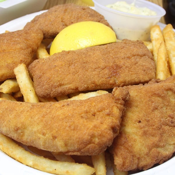 A plate of golden-brown fried fish and french fries with a lemon wedge and tartar sauce.