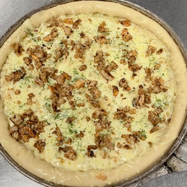 Backwoods Pizza's chicken alfredo pizza with a thick crust, white sauce, chicken, and parsley.