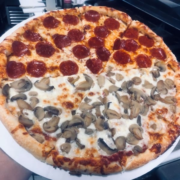A large Backwoods Pizza with half pepperoni and half mushroom toppings, sliced and ready to eat.
