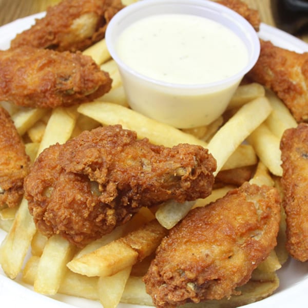 Crispy fried chicken wings and golden french fries with a side of ranch dressing.