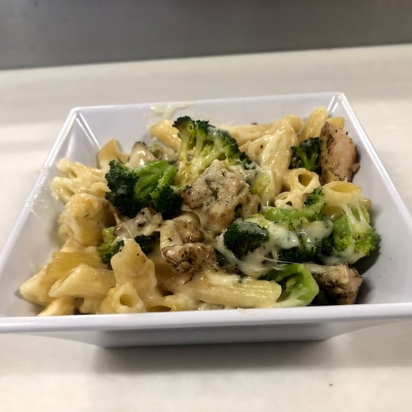 Creamy pasta with chicken and broccoli in a white square bowl from Backwoods Pizza.